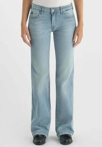 Jean flare bleu clair en denim avec une finition délavée, cinq poches et des coutures contrastées. Se ferme avec un bouton et un zip.