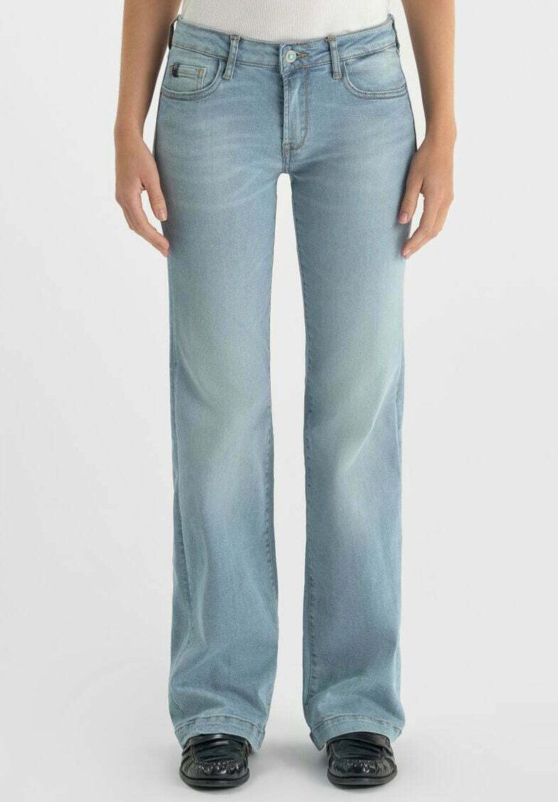 Jean flare bleu clair en denim avec une finition délavée, cinq poches et des coutures contrastées. Se ferme avec un bouton et un zip.