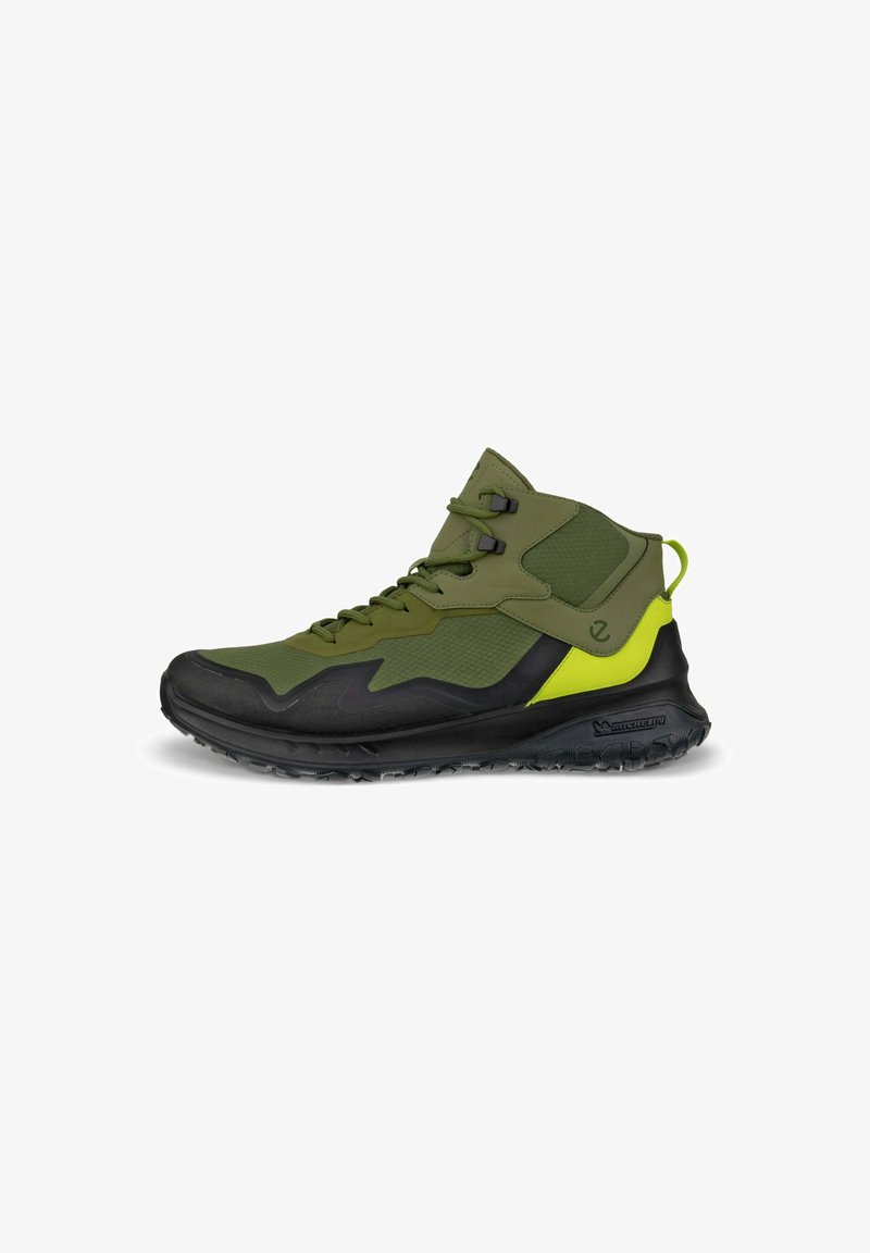 Scarpa da trekking mid-top verde e nera con tomaia texturizzata, suola in gomma e accenti giallo neon. Presenta lacci e un colletto imbottito.