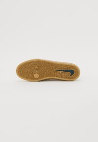 Nike-Schuhsohle mit einem strukturierten Gummi-Design, das Zickzackmuster und ein schwarzes Swoosh-Logo aufweist. Flache und breite Form für Stabilität.