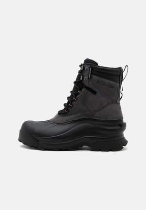 Botte d’hiver imperméable Columbia isolée noire et grise avec semelle robuste et lacets à l’avant, conçue pour le froid et une utilisation extérieure.