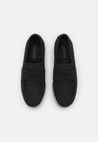 Black slip-on shoes with a suede-like texture, featuring a flat sole, crossband design, and a soft interior lining.
