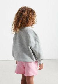 Hallide hallide särk ümmarguse kaelusega, millele on sobitatud roosad lühikesed püksid, millel on toore äär. Kangas on pehme ja kerge struktuuriga.