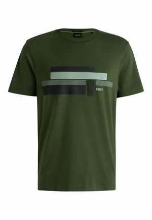 Olivgrön bomull t-shirt med rund halsringning. Har lager med grafiska ränder i ljusgrön, svart och mönstrade texturer. Logotyp på framsidan.