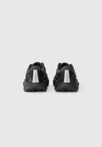 Chaussures de sport noires avec une tige en maille et synthétique, col rembourré, accents réfléchissants et semelle en caoutchouc texturé. Vue arrière montrée.