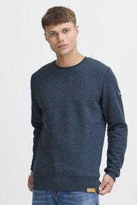 Sudadera azul marino hecha de una tela suave, con un cuello redondo, mangas largas y una etiqueta tejida como acento en el dobladillo.