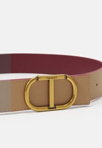 Cintura in pelle tan e bordeaux con fibbia ovale in tonalità oro e incisione "TWINSET", caratterizzata da una texture liscia.