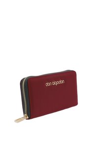 Cartera roja con cremallera y un logotipo dorado, con una textura suave y un acento negro contrastante a lo largo de la cremallera. Diseño minimalista.
