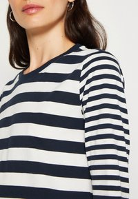 Marineblau und weiße gestreifte Langarmbluse mit Rundhalsausschnitt, aus weicher Baumwolle gefertigt, mit gleichmäßigen horizontalen Linien und einem entspannten Schnitt.