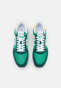 Um par de sapatilhas Armani Exchange em verde, branco e amarelo com atacadores brancos, vistas de cima sobre um fundo branco.