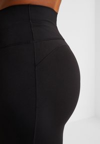 Leggings negros de cintura alta con una textura suave, que presentan un detalle de costura y una silueta ajustada, diseñados para la comodidad y la flexibilidad.