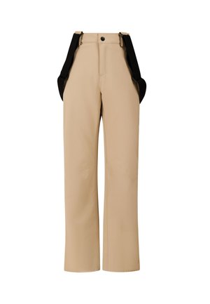 Enfant portant un haut bleu à manches longues, un pantalon de neige beige avec des bretelles noires, des bottes d'hiver noires et un bonnet bleu foncé, debout devant un fond gris.