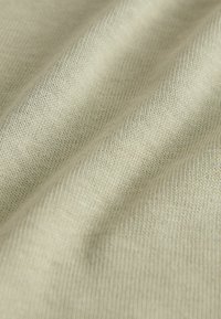 Hellbeiges Strickgewebe mit feiner, strukturierter Webart, das eine weiche Drapierung und einen leichten Glanz zeigt. Geeignet für Bekleidung oder Accessoires.