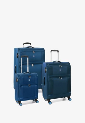 Set di tre valigie blu opache con texture lisce, multiple tasche e quattro ruote ciascuna. Manici telescopici e chiusure a zip.