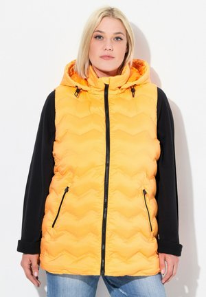 Gefütterte ärmellose Jacke in hellorange mit Kapuze, schwarzen Ärmeln, Reißverschlusstaschen und einem Zickzack-Steppmuster.