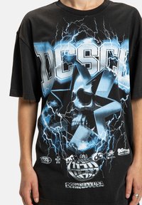Sort bomulds t-shirt med et stort grafisk print af et kranium og en stjerne med blå lyn-effekter; løs pasform med kortærmer.