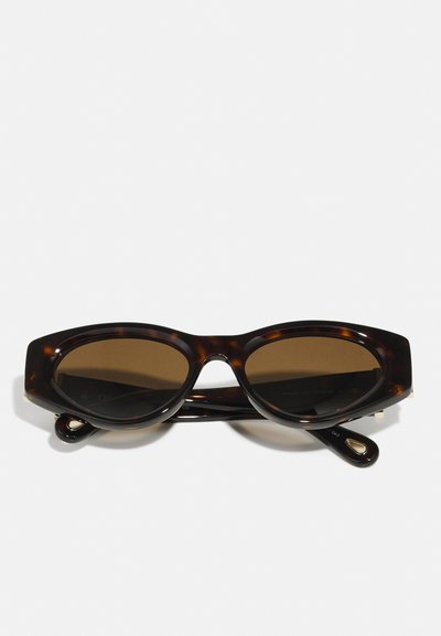 schildpad zonnebril met bruin getinte lenzen, cat-eye vorm, glanzende afwerking en metalen accenten op de tempels.