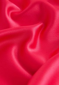 Élénkpiros szatén anyag, sima, fényes felülettel, enyhe redőkkel és hullámokkal, amelyek visszaverik a fényt és mélységet mutatnak.