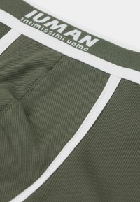Olivově zelené pánské boxerky s jemným žebrováním. Bílý elastický pás má logo "JUMAN intimissimi uomo". Bílé akcenty po stranách.