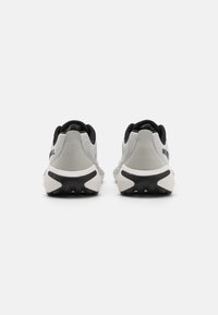 Zapatillas deportivas grises con parte superior de malla, acentos negros, suela acolchada y suela de goma texturizada, vistas desde la parte posterior.