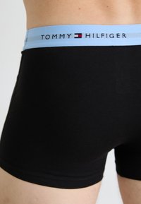 Fekete pamut boxer alsónadrág világoskék elasztikus derékszíjjal, amelyen a "TOMMY HILFIGER" logó jól láthatóan szerepel. Sima tapintás, testhezálló kialakítás.