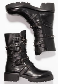 Czarne skórzane botki za kostkę z wieloma paskami ozdobionymi ćwiekami, klamrami i bocznym zamkiem. Gruba, protektorowa podeszwa zapewniająca przyczepność i trwałość.