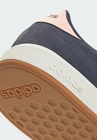 Marinblå mockasinsneaker med ljusrosa accent, vit mellansula och yttersula i gummimaterial med ett texturerat hexagonmönster.