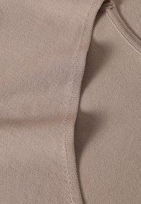 Beige kangas, jossa on sileä pinta, yksinkertainen muotoilu ja ommellut reunat. Materiaali näyttää joustavalta ja pehmeältä.