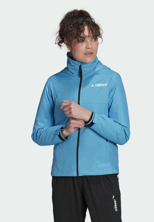 Chaqueta Terrex de color azul claro con cuello alto, cierre de cremallera frontal y acentos negros en contraste. Presenta una tela elástica y bolsillos.