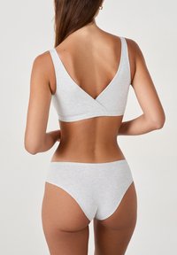 Bralette gris sans coutures avec des bretelles larges et un dos en V, assorti à un slip bikini taille basse, le tout en tissu doux et léger.