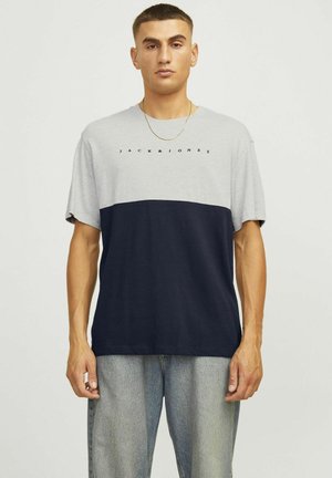 T-maica s kratkim rukavima u sivoj i mornarsko plavoj boji s blokovima boja. Ima okrugli izrez i otisnuti logotip "JACK & JONES" na prsima. Pamuk.