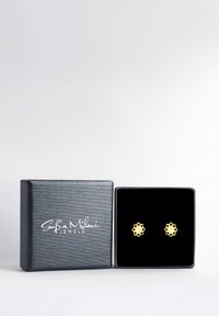 Goldene blumenförmige Ohrringe, die in einer mit schwarzem Samt ausgekleideten Schmuckschatulle präsentiert werden. Die Schatulle ist aus strukturiertem Schwarz und hat ein weißes Logo auf der Vorderseite.