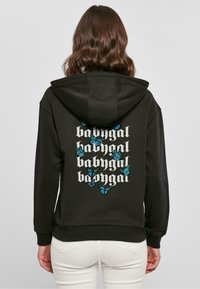 Fekete kapucnis pulóver, amelynek hátulján nagy grafika található, ismétlődő "babygal" felirattal és kék pillangó illusztrációkkal. Pamut keverék anyag.
