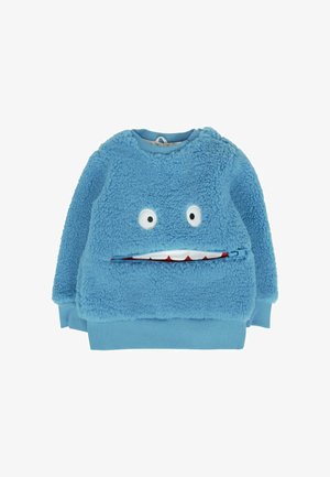Pull en peluche bleu pour enfants avec deux yeux de dessin animé et un design de bouche zippée montrant des dents blanches avec des gencives rouges.