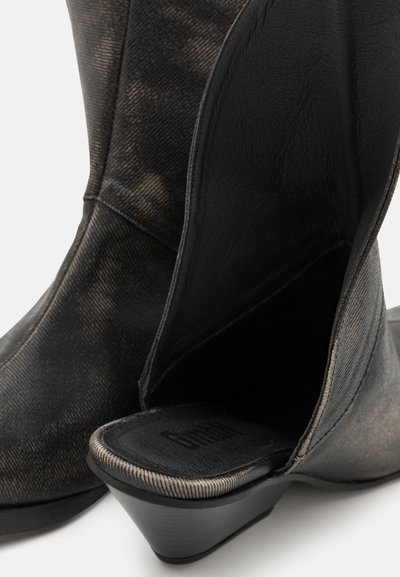 Bottines noires avec une finition texturée, dotées d'un talon effilé, d'un intérieur lisse et de détails de couture subtils.