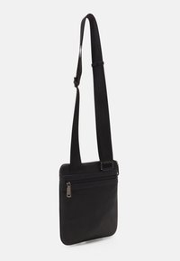 Svart crossbody-väska med en strukturerad yta, utrustad med en lång justerbar rem, överdel med dragkedja och en framficka med dragkedjestängning.