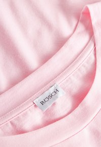 Rosa bomull T-shirt med rund hals och en etikett som läser "RÖSCH." Slät yta med fin söm längs halsringningen.