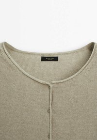 Maglione beige lavorato a maglia con scollo rotondo, caratterizzato da una chiusura con bottoni sul davanti e una texture sottile. Etichetta visibile all'interno del colletto.