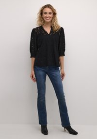 Black lace top with v-neck and 3/4 puffed sleeves, paired with blue straight-leg jeans and black heeled ankle boots.