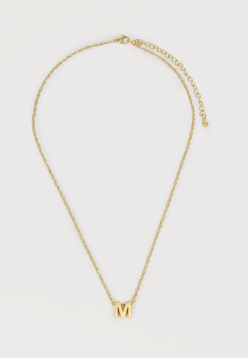 Χρυσό κολιέ με μενταγιόν σε σχήμα του γράμματος "M" και ρυθμιζόμενο κούμπωμα σε λευκό φόντο.