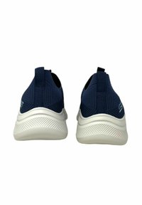 Sneaker in maglia blu navy scuro con design slip-on, suole intermedie bianche, suole in gomma testurizzata e rinforzi sul tallone.