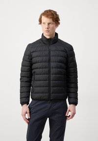Black puffer jacket with a high collar, zip closure, and horizontal stitching. Features side pockets and a logo on the left sleeve.