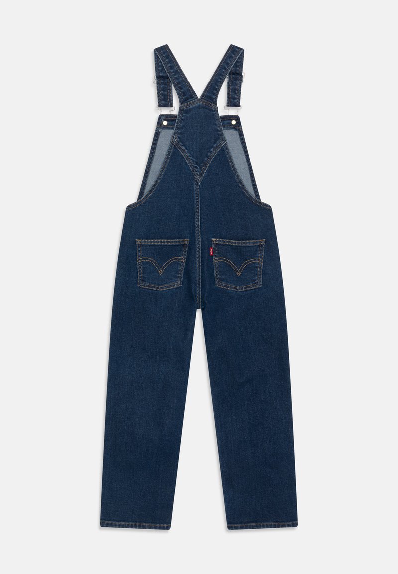 Jeans-Latzhose mit verstellbaren Trägern, dunkelblauer Farbe, zwei Fronttaschen mit bogenförmigen Nähdetails, weit geschnittenen Beinen und verstärkten Nähten.