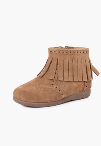 Botín de ante marrón con detalles de flecos, acentos perforados, puntera redonda y suela de goma plana. Cierre con cremallera en la parte trasera.