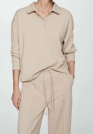 Beige pullover med krave, tre knapper og sænkede skuldre. Sammen med matchende beige bukser med snoretræk, der viser en blød tekstur.