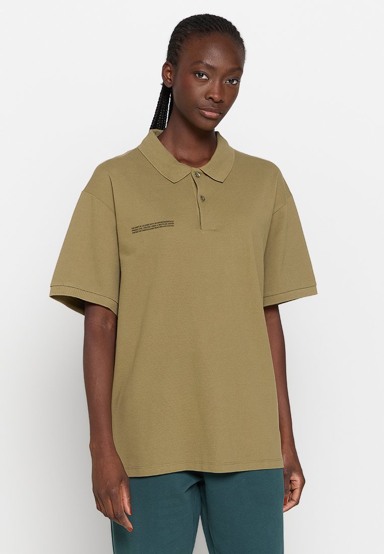 Polo de color verde oliva hecho de algodón texturizado, con cuello y mangas cortas. Incluye un detalle impreso en el lado izquierdo del pecho.