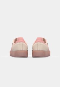 Hellrosa Sneakers mit strukturiertem Obermaterial und kontrastierenden mauvefarbenen Akzenten. Rundliche Form und Gummisohle. Minimalistisches Design mit gesteppten Details.
