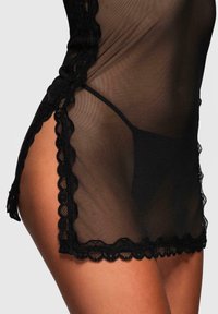 Chemisier in tessuto nero trasparente con bordo in pizzo scallop, presenta uno spacco laterale e una copertura minima, evidenziando la delicata texture e design.