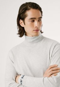 Maglione a collo alto grigio chiaro realizzato in morbido tessuto, con collo e polsini a costine e dettagli del logo "Pepe Jeans" blu sul polso.