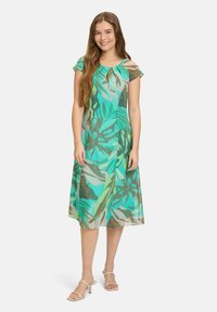 Kwiatowa sukienka w odcieniach turkusu, zieleni i brązu. Lekki materiał, krótkie rękawy, długość do kolan, swobodny krój i okrągły dekolt.